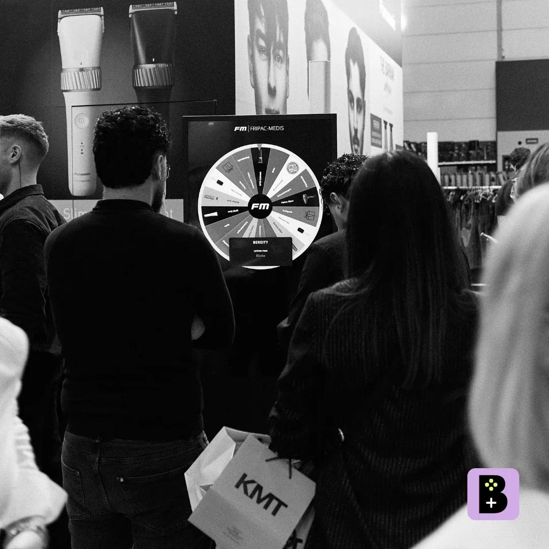 Besucher am Glücksrad auf dem großen Screen der Tophair-Messe